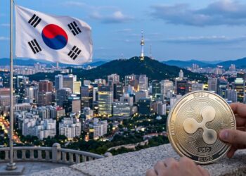 Una moneda metálica de Ripple USD (RLUSD) en primer plano con el horizonte urbano de Seúl y la bandera de Corea del Sur de fondo.