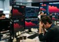 Inversionista preocupado en una oficina ante monitores que muestran gráficos en rojo con caídas en el mercado de stablecoins como USDT.