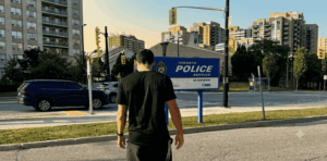 Fotografía de primer plano de un formulario policial de papel impreso en blanco y negro, con el encabezado visible que dice "TORONTO POLICE SERVICE 22DIVISION West MToronto". El documento reposa sobre una mesa de madera clara, junto a un teléfono fijo y un cuaderno de notas. La imagen transmite la frialdad burocrática del proceso legal que enfrentan las víctimas de robos de criptomonedas, en contraste con la naturaleza digital e intangible de los activos perdidos.