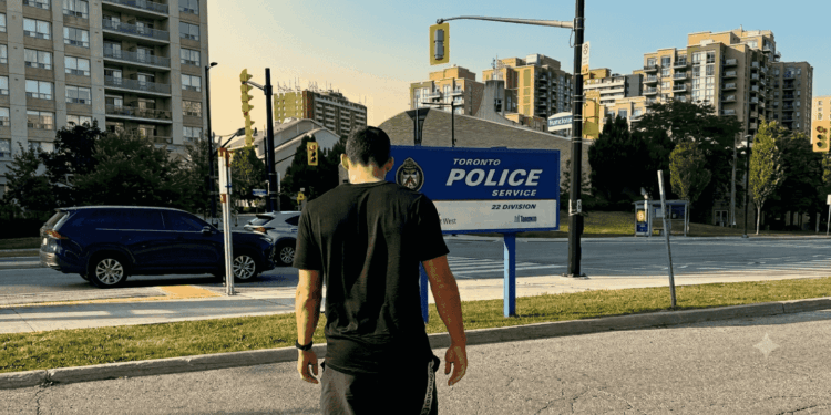 Fotografía de primer plano de un formulario policial de papel impreso en blanco y negro, con el encabezado visible que dice "TORONTO POLICE SERVICE 22DIVISION West MToronto". El documento reposa sobre una mesa de madera clara, junto a un teléfono fijo y un cuaderno de notas. La imagen transmite la frialdad burocrática del proceso legal que enfrentan las víctimas de robos de criptomonedas, en contraste con la naturaleza digital e intangible de los activos perdidos.