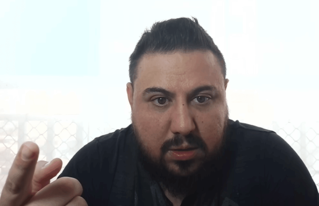 Primer plano de Felipe Ojeda, un hombre de barba corta y camiseta oscura que mira seriamente a la cámara con expresión de enfado o indignación, mientras señala con el dedo hacia el espectador durante una transmisión en video frente a una ventana luminosa.