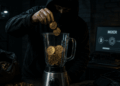 Persona encapuchada metiendo monedas de bitcoin en una máquina mezcladora.