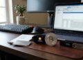 Una moneda de bitcoin en un escritorio con hardware wallets y laptops.