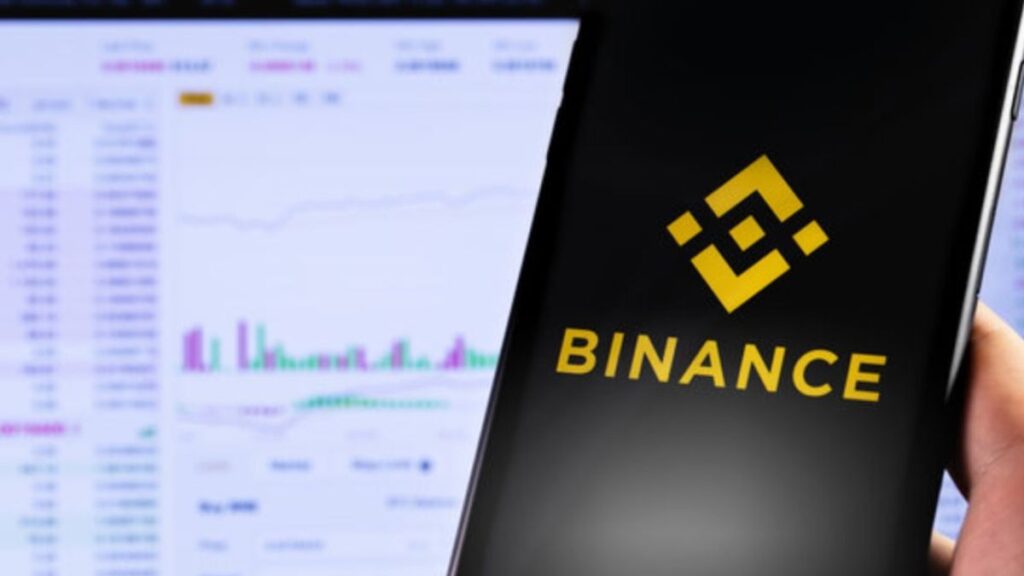 Mano sujetando un teléfono inteligente que muestra el logo de Binance.