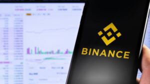 Mano sujetando un teléfono inteligente que muestra el logo de Binance.