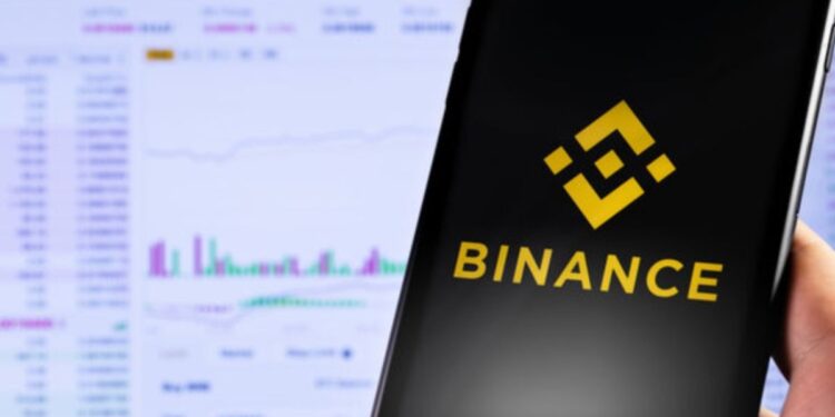 Mano sujetando un teléfono inteligente que muestra el logo de Binance.