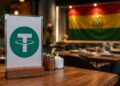 Cartel con el logo de Tether (USDT) en la mesa de un restaurante con la bandera de Bolivia al fondo.