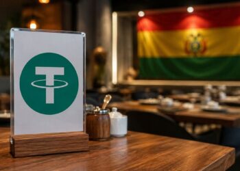 Cartel con el logo de Tether (USDT) en la mesa de un restaurante con la bandera de Bolivia al fondo.