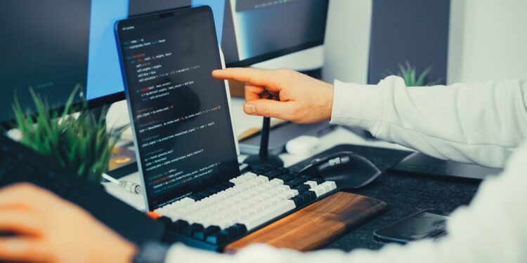 Hombre de camisa blanca usando tablet que muestra códigos en pantalla