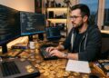 Un desarrollador de software con monedas de bitcoin alrededor.