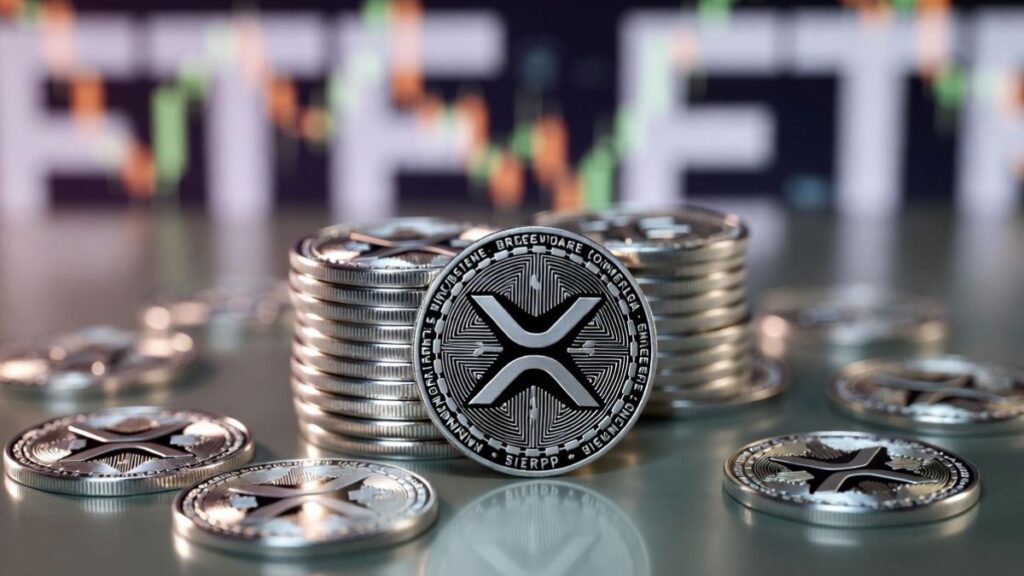 Monedas físicas de XRP y al fondo, desenfocado, aparece un gráfico de precios.