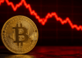 Moneda de bitcoin y flecha roja descendente.