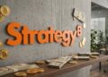 Logo de Strategy sobre una pared con monedas de bitcoin y dólares en efectivo.
