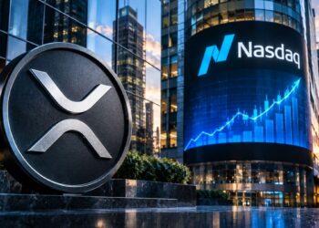 Moneda plateada con el logo de XRP en primer plano frente a una pantalla del edificio Nasdaq.