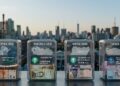 Cuatro contenedores de vidrio transparente ubicados sobre una superficie metálica frente a un panorama urbano iluminado por la luz del atardecer. Cada contenedor incluye fajos de billetes de las monedas locales de Argentina, Venezuela, Nigeria y Turquía.