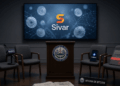 Sala de prensa oficial vacía en El Salvador. Al centro, un atril con el escudo nacional y una pantalla encendida que muestra el logotipo de Sivar sobre stablecoins digitales. Alrededor, cuatro sillas vacías: una con micrófono de Bloomberg, otra con teléfono de Coinbase, otra con carpeta sellada con cinta roja marcada "contrato" y otra con placa de la Oficina de Bitcoin. En el suelo, un periódico con el titular "Government-backed" parcialmente visible. No hay personas. Iluminación fría, composición simétrica, atmósfera de contradicción.