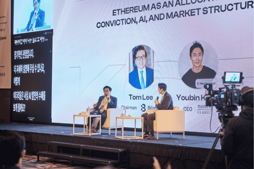Tom Lee y Youbin Kang conversan en el escenario de Ethereum Korea en Seúl frente a una pantalla que presenta Ethereum como convicción de asignación, IA y estructura de mercado.