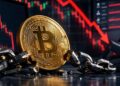 Moneda de Bitcoin dorada sobre una cadena metálica rota.