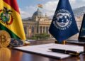 Banderas de Bolivia y el FMI con criptomonedas y documento en escritorio.