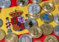 Muchas criptomonedas y detrás la bandera de España.