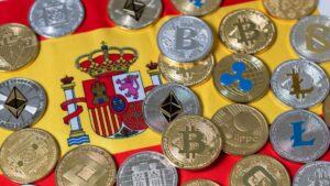 Muchas criptomonedas y detrás la bandera de España.