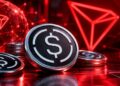Monedas físicas con el logo de USDe y el logotipo de TRON sobre un fondo rojo digital de alta tecnología.