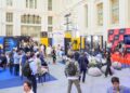 Asistentes recorren stands y siguen un panel en el escenario de MERGE Madrid