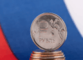 Una moneda de rublo de Rusia y detrás la bandera de Rusia