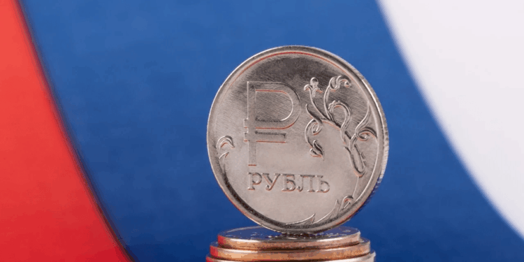 Una moneda de rublo de Rusia y detrás la bandera de Rusia