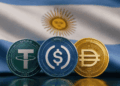 Monedas de USDT, USDC y DAI en primer plano. Bandera argentina en el fondo.