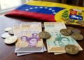 Billetes venezolanos junto a monedas de USDT y la bandera de Venezuela en el fondo.