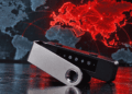 Primer plano: dispositivo Ledger. En el fondo: mapa mundial con Europa y Asia pintadas de rojo.