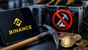 Tablet con el logo de Binance junto a monedas de bitcoin y criptomonedas, un pico y un símbolo de prohibido sobre un equipo de minería.