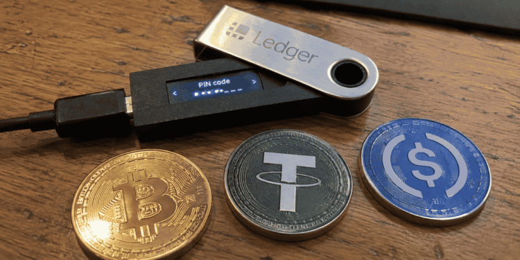 Dispositivo ledger junto a monedas de bitcoin, usdt y usdc.