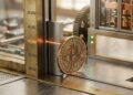 Moneda de Bitcoin cruzando un sensor láser marcando la cifra 84.000 en un mecanismo conceptual.