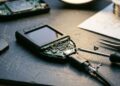 Dispositivo de hardware wallet de criptomonedas abierto y modificado con herramientas de precisión sobre una mesa de trabajo.